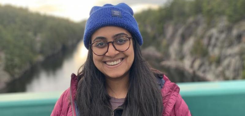 Aarohi Pathak smiling by a lake in the mountains.