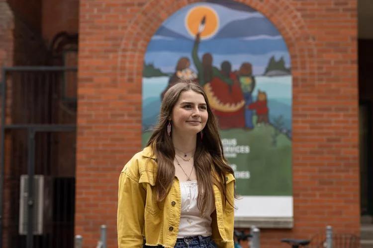 Alicia Corbierre standing outside with a mural behind her