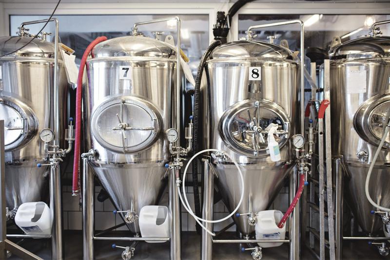 Metal brewing vats look like giant coffee dispensers linked by tubing and industrial gauges.
