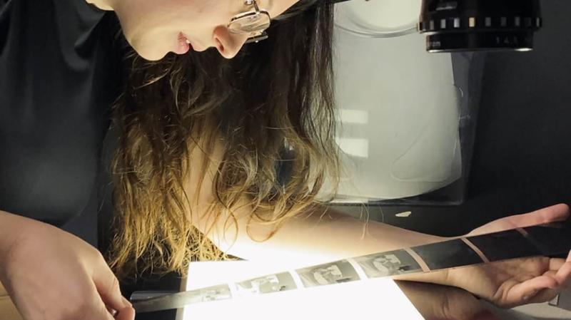 A woman looking at film negatives above a light