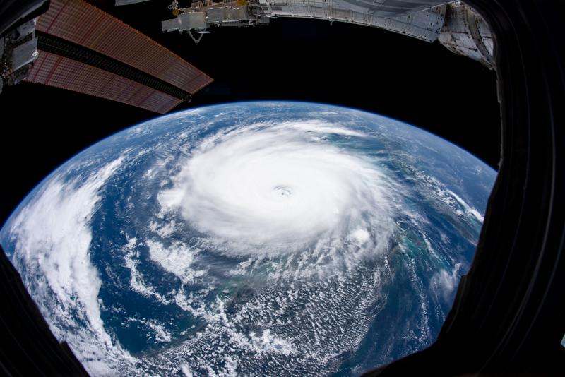 The swirl of Hurricane Dorian covers a large curved segment of the Earth below a metal wing of the International Space Station.