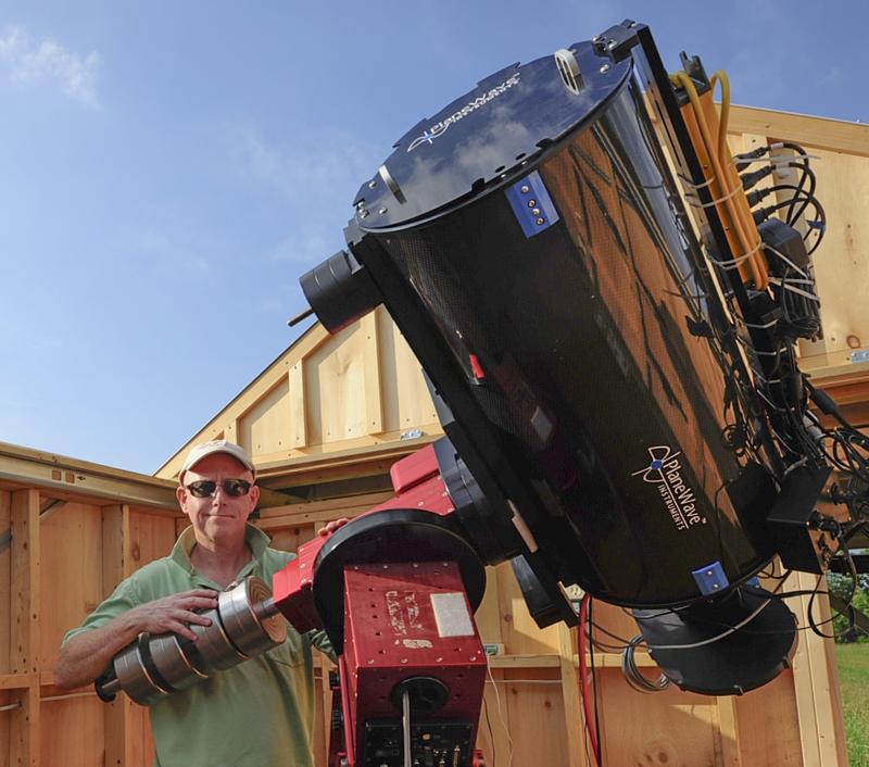 Stuart Heggie stands outside with his telescope.