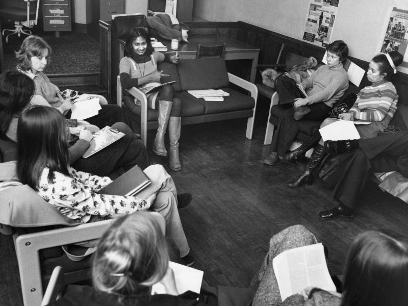 An old photograph from 1975 shows young women gathered in a circle, on comfy chairs, around Ceta Ramkhalawansingh.