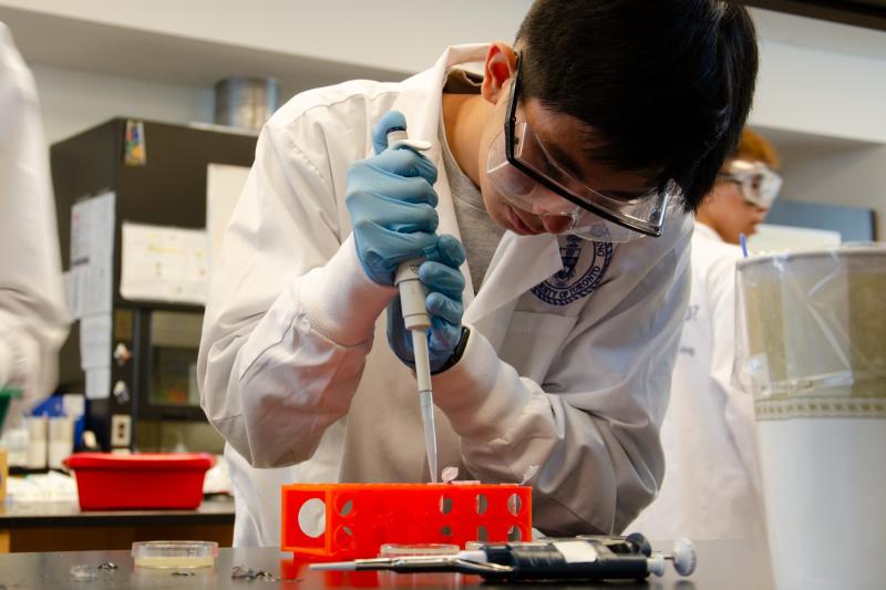 A high school student using a pipette in a science lab