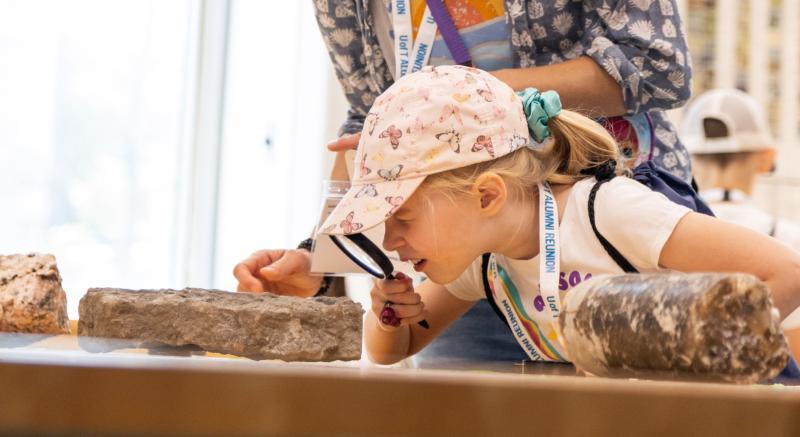 Child looking at rock through a magnifying glass