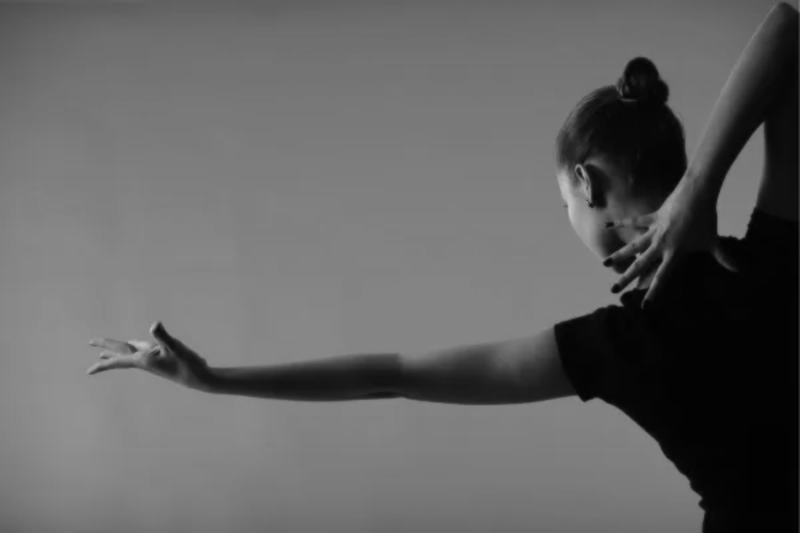 A contemporary dancer striking an artistic pose with their arm extended.