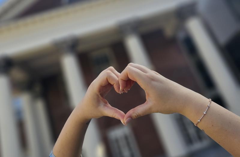 Two hands forming a heart with Flavelle House in the background