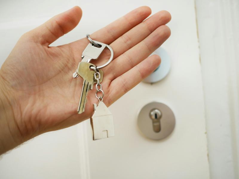 An open palm with keys resting on it, with a door in the background.