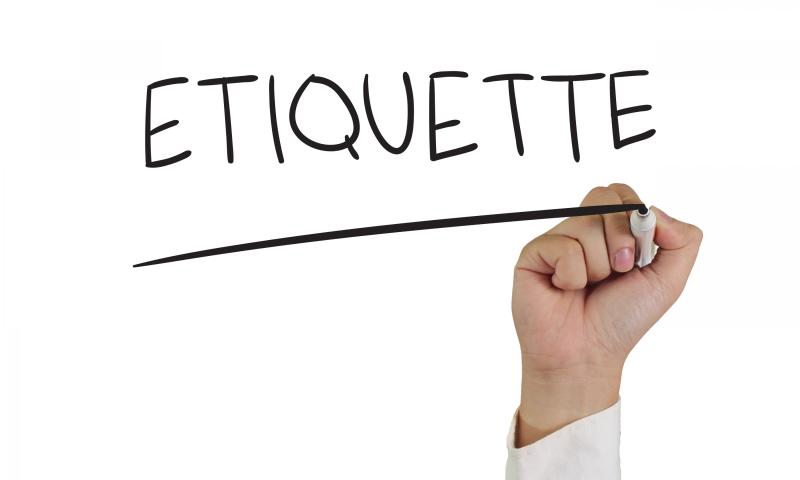 a hand holding a marker with the word "etiquette" on a white board.