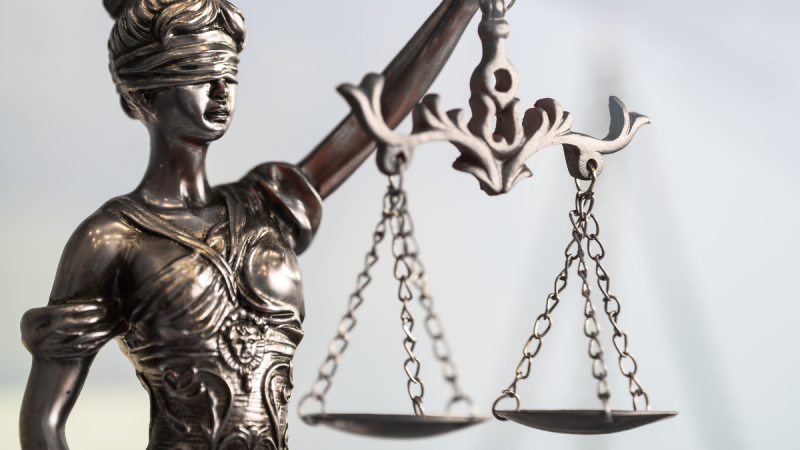 Bronze Lady Justice holding scale with one hand and blindfolded.