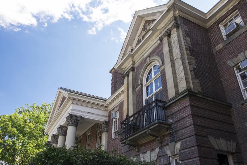 Exterior photo of Jackman Law Building at the University of Toronto against blue sky, clouds and trees.  