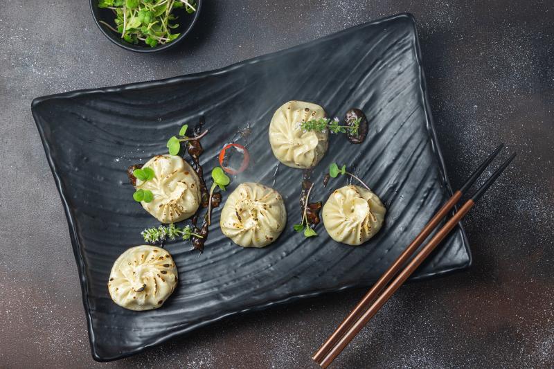 5 Dim Sum dumplings on a black rectangular dish