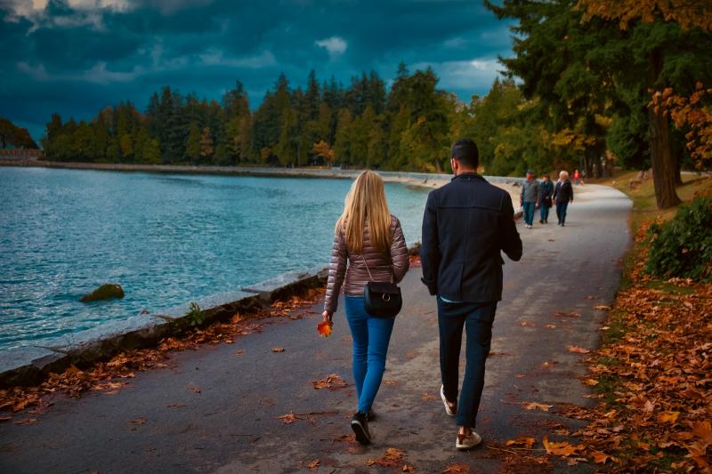 Two people walking along the water with on an autumn day