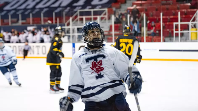 Women's hockey player celebrates after a goal while looking into the crowd.