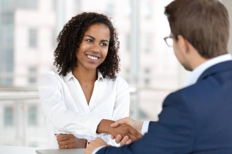 Smiling African HR manager handshake hire candidate at job interview.