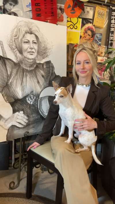 Erin Finley sits in her art studio holding her dog.