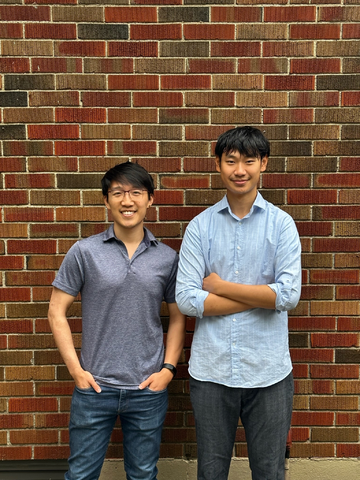 Two men standing in front of a brick wall