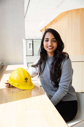Twinkle Choubey smiles as she sits at a table, holding a hard hat.