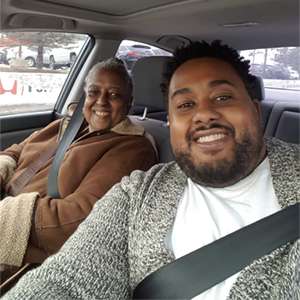 Keon Priestley and his mom Marie smile happily as they sit in a car together.