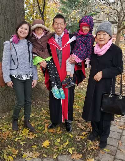 David standing outside at U of T with his family 