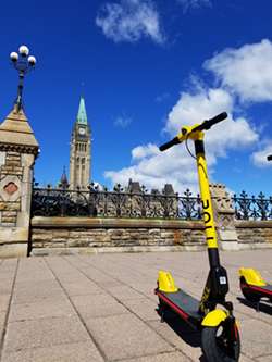 A scooter sits on the pavement in front of the Parliament Buildings in Ottawa.