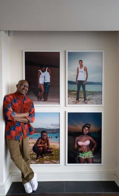 Kenneth Montague standing in an alcove that contains four large photographs of Black people in different settings.