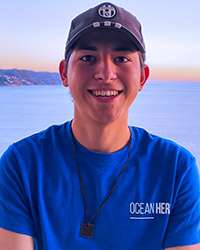 Diego Arreola Fernández smiles, standing on a beach at sunset.