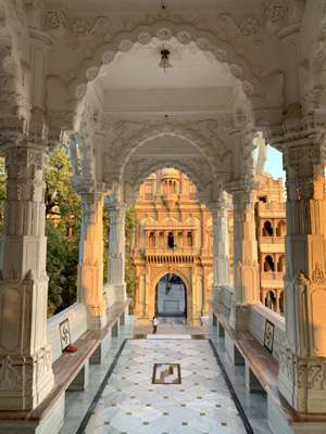 Sunset light falls on elaborately carved arches above a marble floor at BAPS Swaminarayan Mandir.