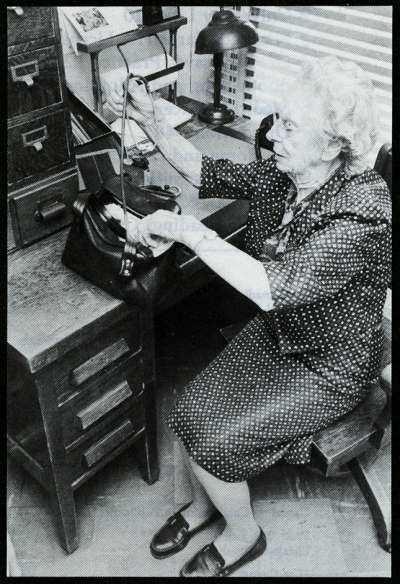 Dr. Elizabeth Bagshaw sitting at a desk, putting a stethoscope into her bag.