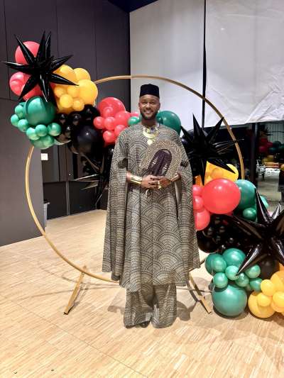 A Black man standing in front of balloons 