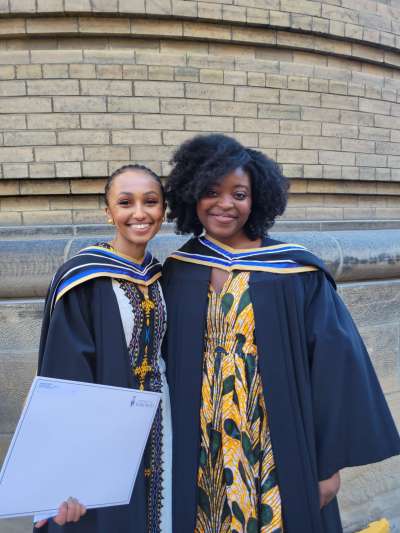 Gemma Retta and Gemma Kabeya in their graduation gowns, smiling. 