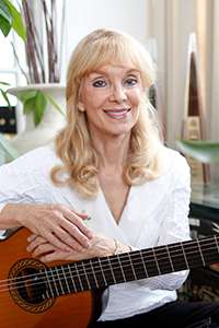 Liona Boyd smiling and holding a guitar.