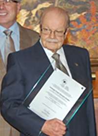 Frank Hooper holding a framed award.