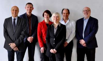 The six professors who run the Jackman Scholars-in-Residence program stand together, smiling.