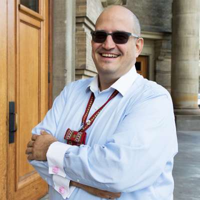 Jason Bazylak smiles while standing in the porch outside Convocation Hall.