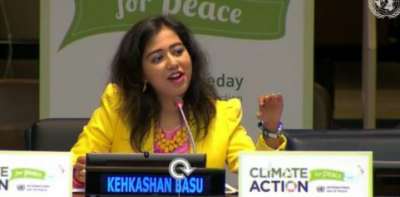 Kehkashan Basu gestures as she speaks at a podium labelled: Climate Action for Peave