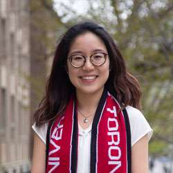 Kim Watada smiling and wearing a University of Toronto scarf.