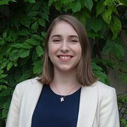 Laura Berneaga smiles and stands in front of an ivy-covered wall.