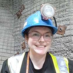 Marie-Eve Caron smiling and wearing a hard hat on a construction site.