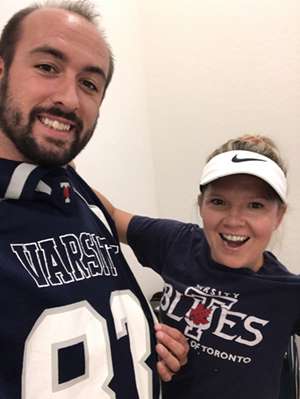 Masha and Cory Kennedy smile as they take a selfie, wearing Varsity Blues shirts.