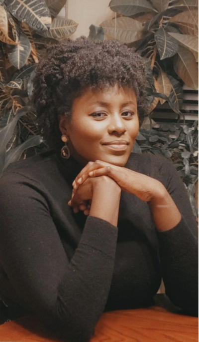 Nana Frimpong smiles as she leans on a desk.