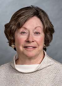 Joan Johnston smiling in front of grey background