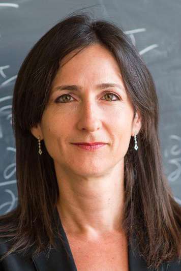 Sara Seager smiles slightly while standing in front of a classroom chalkboard.