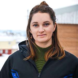 Sarah Clark smiles, standing outdoors in a snowy town.