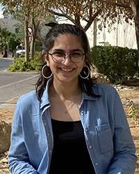 Maansi Suri smiles, standing in a garden.