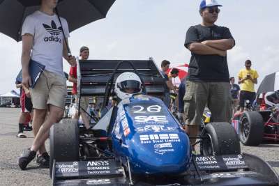 Two students stand on either side of the U of T racing car as it takes position on the start grid at the Pittsburgh International Race Complex.