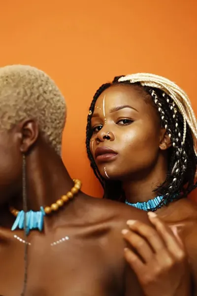 Two people in front of an orange backdrop