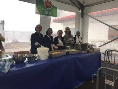 Aarohi Pathak and friends, wearing hairnets and gloves, stand behind a table of food ready to serve templegoers.
