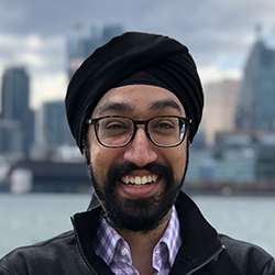 Akshdeep Bhatia smiles while standing on Toronto's lakeshore.