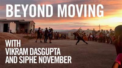 A crowd watch a Black man dance outdoors. Text over image reads, Beyond Moving, with Vikram Dasgupta and Siphe November.